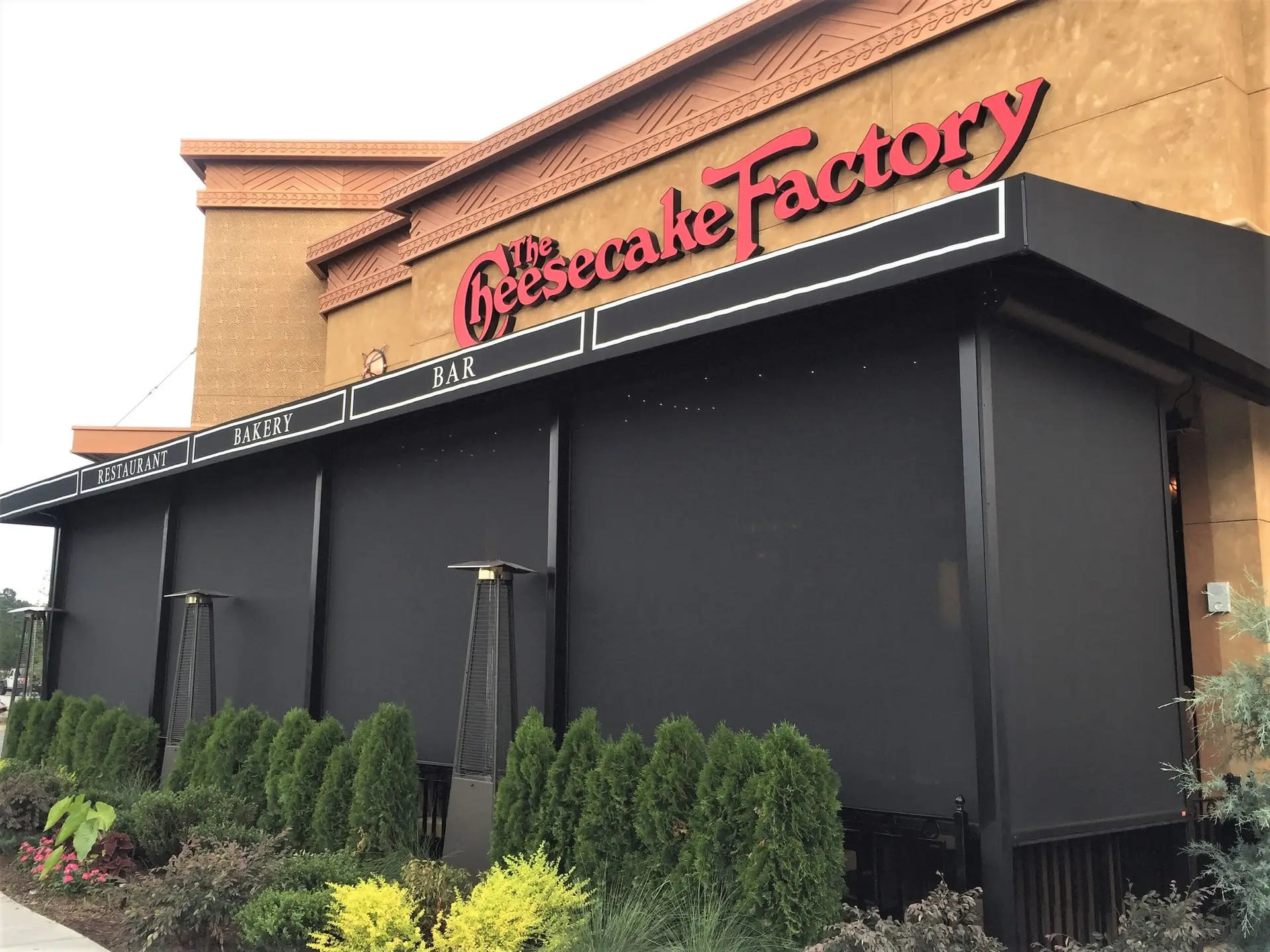 Cheesecake Factory exterior with motorized retractable screens enclosing the outdoor dining area, blending seamlessly with the restaurant’s architectural design.