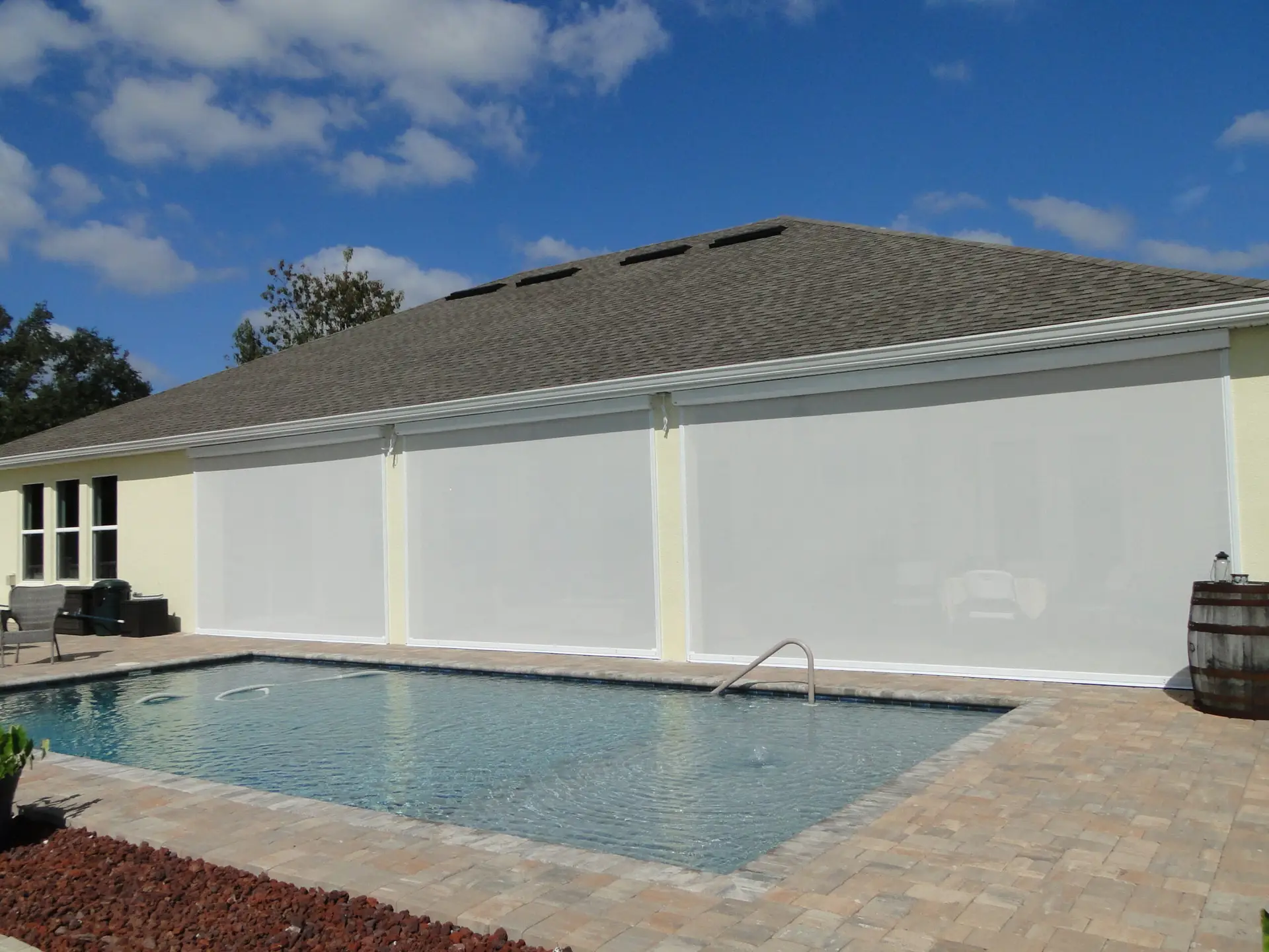 Motorized retractable screen providing shade, privacy, and insect protection for a patio in a modern Florida home.