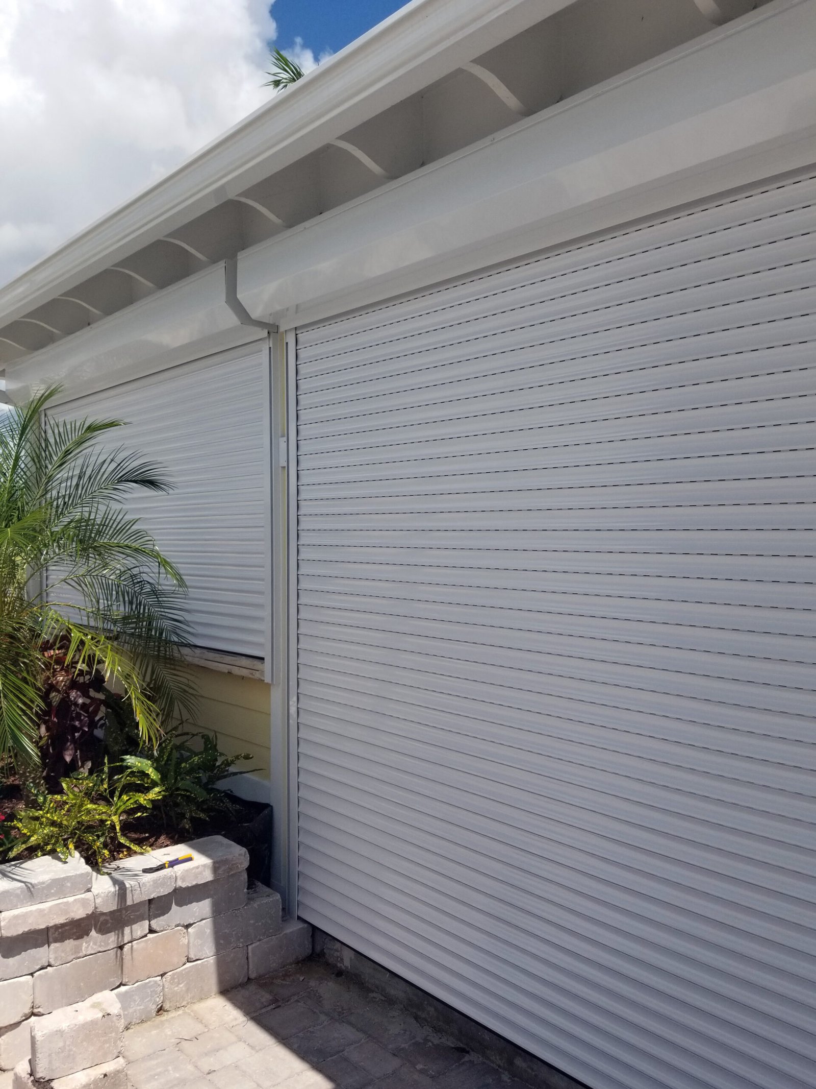 Motorized roll-down aluminum security shutter installed on a home for storm protection, privacy, and enhanced security.