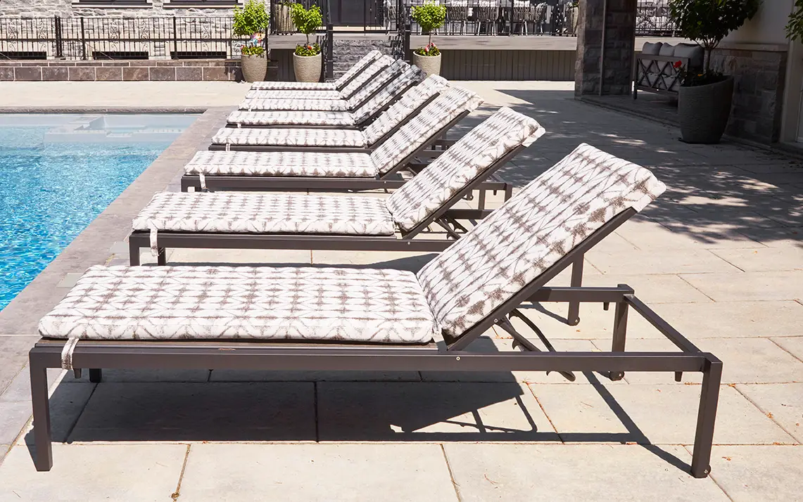 Outdoor furniture collection with white frames, soft cushions, and coastal-inspired styling on a sunlit lanai.